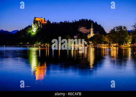 Allumé le château de bled, blejski grad, situé sur un éperon rocheux, vu à travers le lac blejsko jezero à Bled, nuit Banque D'Images