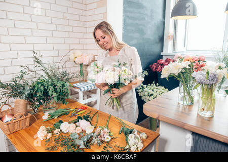 Jolie jeune femme concentrée dans des verres fleuriste travaillant dans le magasin de fleurs Banque D'Images