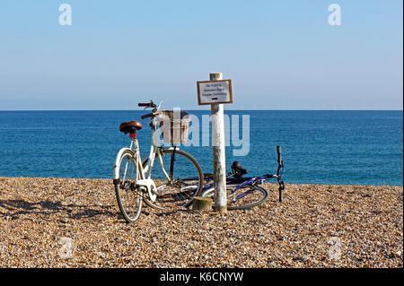 Vue de deux vélos garés sur la crête de galets sur la côte nord du comté de Norfolk à claj-next-the-Sea, Norfolk, Angleterre, Royaume-Uni. Banque D'Images