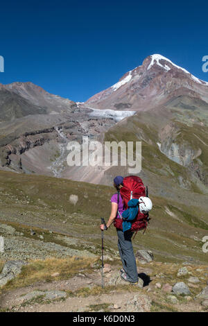 Female hiker à haut vers le sommet du mont Kazbek (Kazbeg) en Géorgie, s'établissant à 5047 mètres au-dessus du niveau de la mer. Banque D'Images