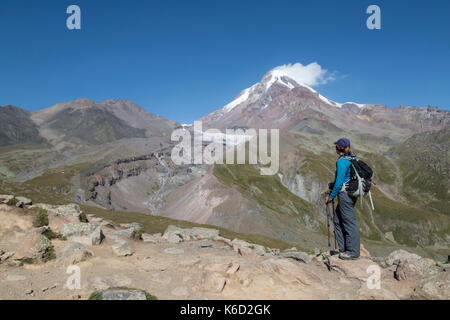 Female hiker à haut vers le sommet du mont Kazbek en Géorgie. La montagne est 5047 mètres au-dessus du niveau de la mer et est situé dans la gamme Khokh. Banque D'Images