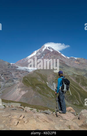 Female hiker à haut vers le sommet du mont Kazbek en Géorgie. La montagne est 5047 mètres au-dessus du niveau de la mer et est situé dans la gamme Khokh. Banque D'Images