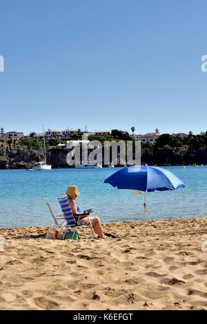 La haute dame âgée à bronzer sur la plage de Arenal den Castell Minorque Minorque espagne Banque D'Images