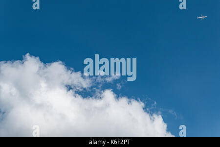 Un avion passant un grand nuage blanc Banque D'Images