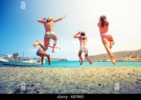 Groupe d'amis de sauter à la mer de la jetée, happy beach holidays, Crète, Grèce