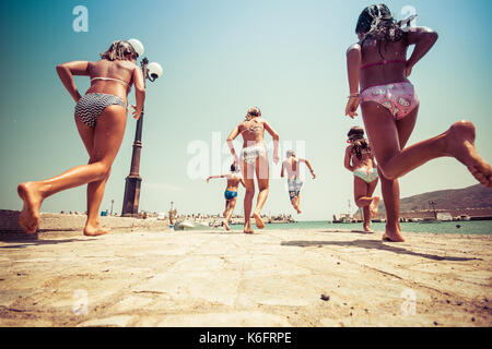 Groupe d'amis de sauter à la mer de la jetée, happy beach holidays, Crète, Grèce
