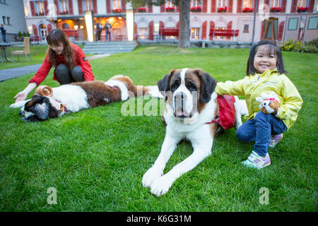 Deux touristes chinois qui posent avec les chiens Saint Bernard, Zermatt, Valais, Suisse Banque D'Images