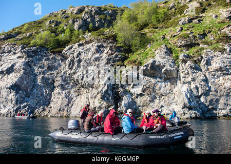 G Adventures passagers des croisières en zodiac canot visiter les mouettes tridactyles nichant sur les falaises en Sundsvollsundet réserve naturelle, la Norvège Banque D'Images