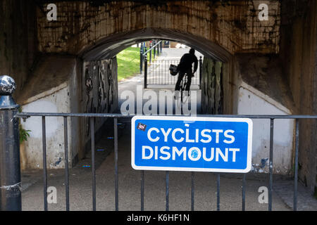 Les cyclistes démonter signe sur sentier sous pont de chemin de fer dans la région de Hackney, Londres, Angleterre, Royaume-Uni, UK Banque D'Images