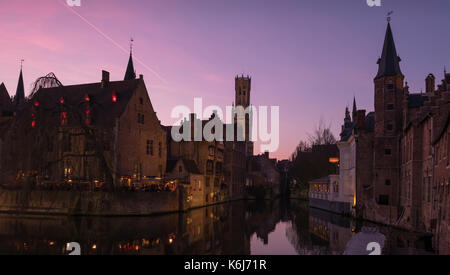 Coucher de soleil romantique sur un magnifique canal dans la vieille ville de Bruges en Belgique avec le beffroi du clocher médiéval dans l'arrière-plan. Banque D'Images