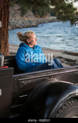 Femme assise en regardant le coucher du soleil, camion rénové Lac Payette, McCall, New York, USA