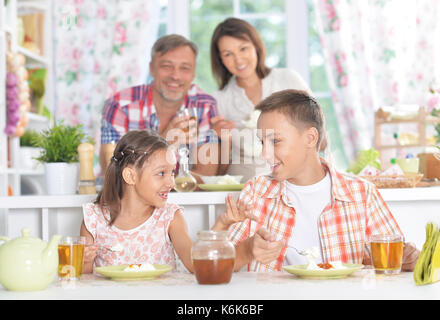 Frère et soeur de prendre le petit déjeuner avec leurs parents sur l'arrière-plan Banque D'Images