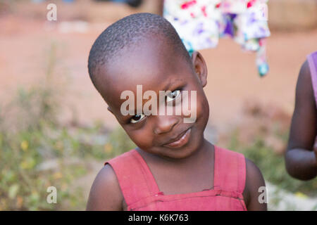 Un mignon petit black preteen girl âge incliner sa tête en souriant. Elle est vêtue d'une robe rouge. Banque D'Images