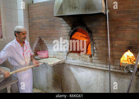 La province du Fars, Shiraz, Iran - 18 avril 2017 : le boulanger se prépare à mettre la pâte dans un four de boulangerie en pierre. Banque D'Images