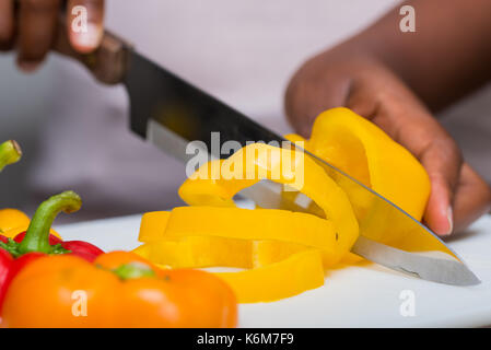 Mains de trancher les poivrons on cutting board Banque D'Images