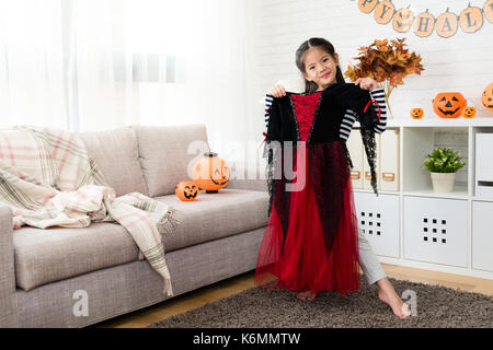 Petite beauté fille préparer pour habiller la sorcière halloween vêtements avant la partie dans la salle de séjour à la maison Banque D'Images