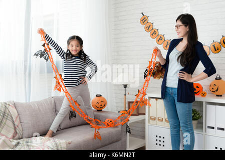 Fille de confiance montrant décoration halloween préparer avec sa mère avant que la fête à la maison Banque D'Images