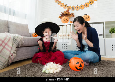 Happy girl le sentiment que la réussite et sa mère choquée de voir beaucoup de bonbons trick ou traiter le jeu de halloween Banque D'Images