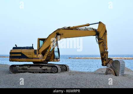 Que l'excavateur travaille sur la plage pour lisser le sable avant le début de la saison d'été Banque D'Images