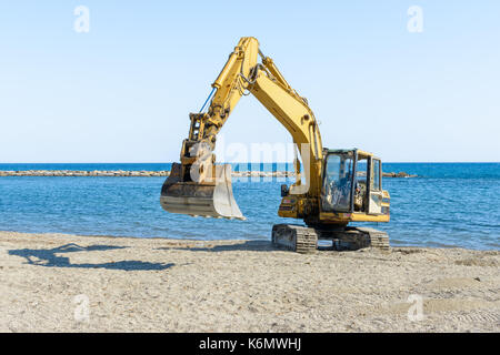 Que l'excavateur travaille sur la plage pour lisser le sable avant le début de la saison d'été Banque D'Images