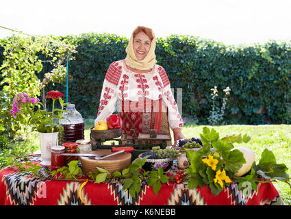 Romanian woman habillés en costume national, montrant les produits agricoles locaux. Banque D'Images