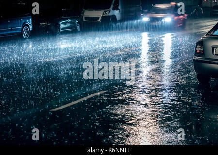 Voiture en mouvement avec les phares allumés lors de fortes pluies de conduite Banque D'Images