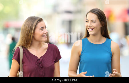 Heureux deux amis marchant vers la caméra et parler dans la rue Banque D'Images