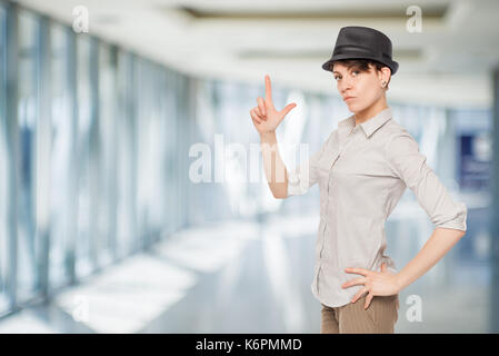 Woman in black hat maintient les doigts dans le bureau des armes à feu Banque D'Images