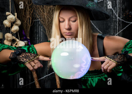 La sorcière regarde dans sa boule magique et essaie de voir l'avenir Banque D'Images