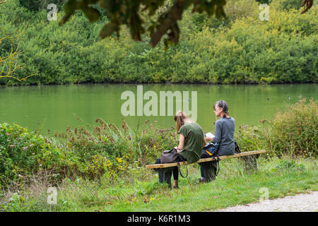 Mother and Daughter sitting ensemble par un lac au début de l'automne au Royaume-Uni. Banque D'Images