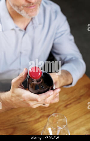 Sélection de vin. man la lecture d'une étiquette sur une bouteille Banque D'Images