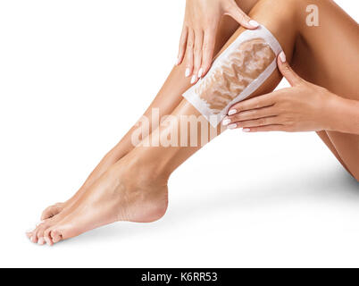 Les jambes des femmes avec des bandes d'épilation à la cire épilation. procédure par bandes. Banque D'Images
