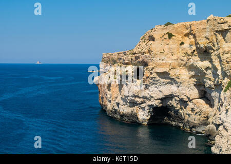 Une falaise de calcaire face dans la côte sud-ouest des îles maltaises, montrant des signes d'érosion de la mer et aux intempéries et une petite grotte. Malte Banque D'Images