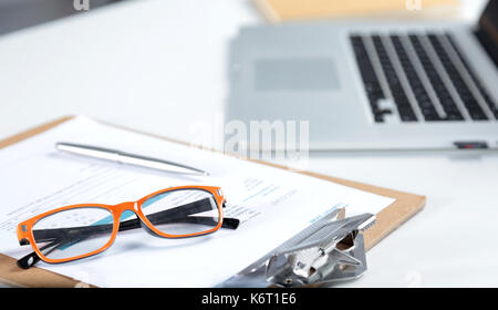 Gros plan du bureau avec ordinateur portable blanc, verres, tasses à café, des bloc-notes et d'autres éléments sur l'arrière-plan de la ville floues Banque D'Images