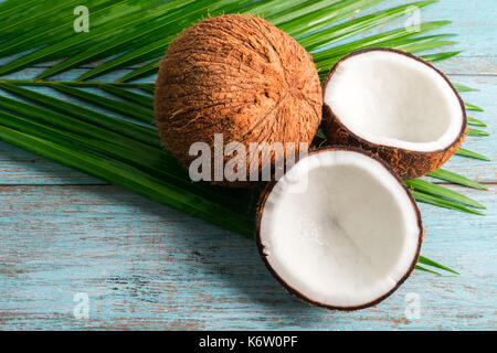 Les moitiés de noix de coco et feuille verte sur fond sombre. Vue de dessus avec copyspace Banque D'Images