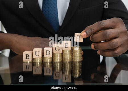 Close-up of businessman mains mettre les lettres du mot budget sur pile de pièces Banque D'Images