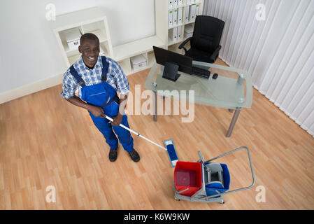 Les jeunes professionnels janitor cleaning signe sol humide Banque D'Images