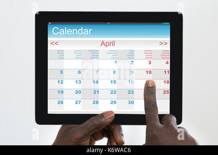 Personne holding digital tablet avec application Calendrier sur l'écran Banque D'Images