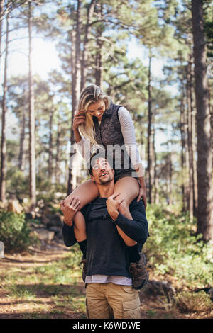 Randonnées couple tout en trekking dans la forêt. Woman riding piggyback sur l'homme au cours de randonnées en forêt. Banque D'Images