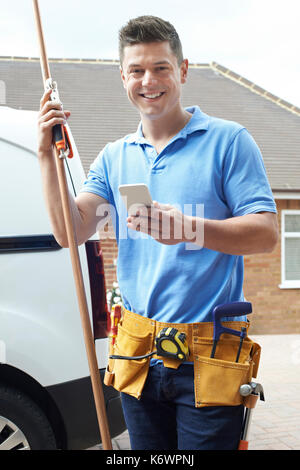 Portrait de plombier avec van de SMS sur téléphone mobile à l'extérieur chambre Banque D'Images