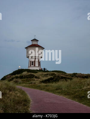 Wasserturm Langeoog. Allemagne Deutschland. Peu après le crépuscule il y a un lever de lune qui se produisent derrière la tour de l'eau, Wasserturm. Le château d'eau est une attraction touristique sur l'île de Langeoog. Le ciel clair permet à la lune d'être vu comme il s'élève au-dessus de la dune de sable que la tour de l'eau a été construit sur. Banque D'Images