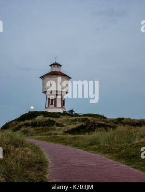 Wasserturm Langeoog. Allemagne Deutschland. Peu après le crépuscule il y a un lever de lune qui se produisent derrière la tour de l'eau, Wasserturm. Le château d'eau est une attraction touristique sur l'île de Langeoog. Le ciel clair permet à la lune d'être vu comme il s'élève au-dessus de la dune de sable que la tour de l'eau a été construit sur. Banque D'Images