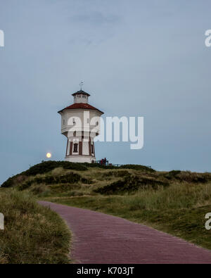 Wasserturm Langeoog. Allemagne Deutschland. Peu après le crépuscule il y a un lever de lune qui se produisent derrière la tour de l'eau, Wasserturm. Le château d'eau est une attraction touristique sur l'île de Langeoog. Le ciel clair permet à la lune d'être vu comme il s'élève au-dessus de la dune de sable que la tour de l'eau a été construit sur. Banque D'Images