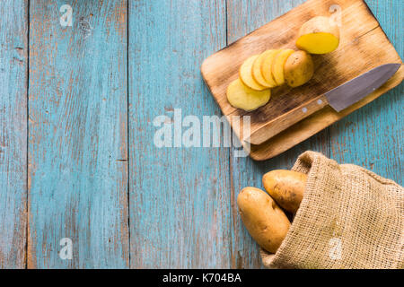 Tas de pommes de terre se trouvant sur des planches de bois avec un sac de pommes de terre dans l'arrière-plan Banque D'Images