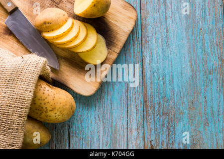 Tas de pommes de terre se trouvant sur des planches de bois avec un sac de pommes de terre dans l'arrière-plan Banque D'Images