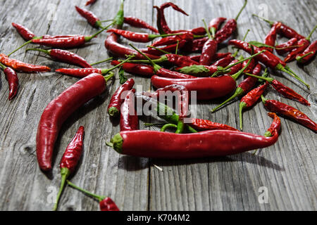 Piments rouges mélangés sur un vieux fond de bois. Banque D'Images