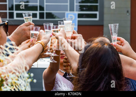 Les invités au mariage de trinquer les verres de champagne avec les jeunes mariés dans l'arrière-plan. Banque D'Images