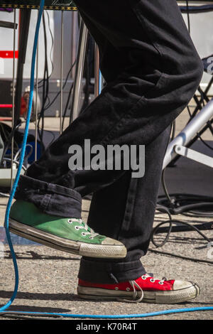 Un musicien de rock avec des baskets rouges et verts se produit dans une piscine en plein air festival de musique local dans la région de Keene, NH. Banque D'Images