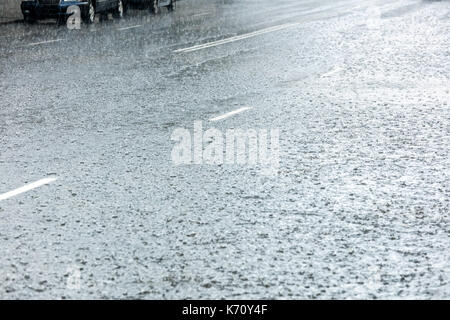 La route d'asphalte inondées avec de l'eau en continu et de gouttes de pluie éclabousse Banque D'Images