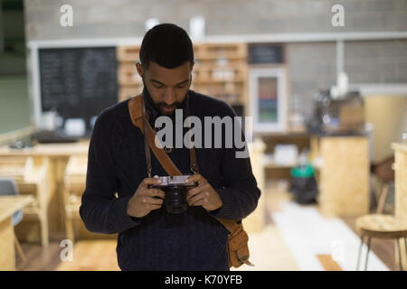 Jeune homme photographier tout en se tenant dans le cafe Banque D'Images